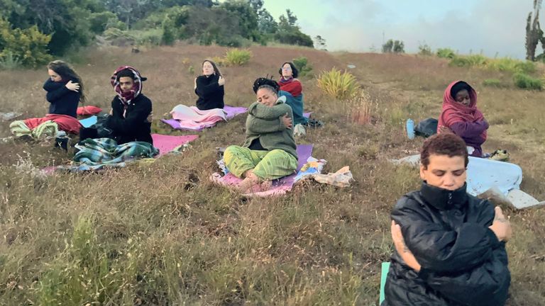 A group sitting on mats on the grass outdoors