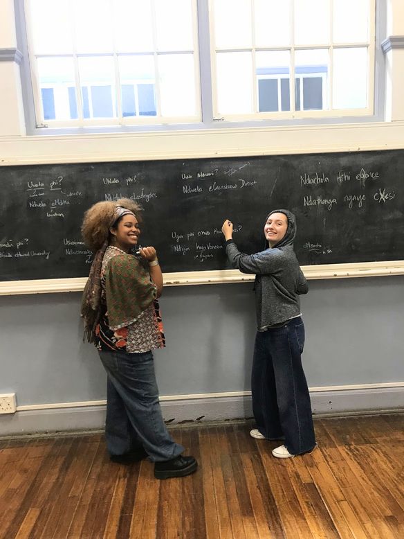 Two students practising isiXhosa at the chalkboard