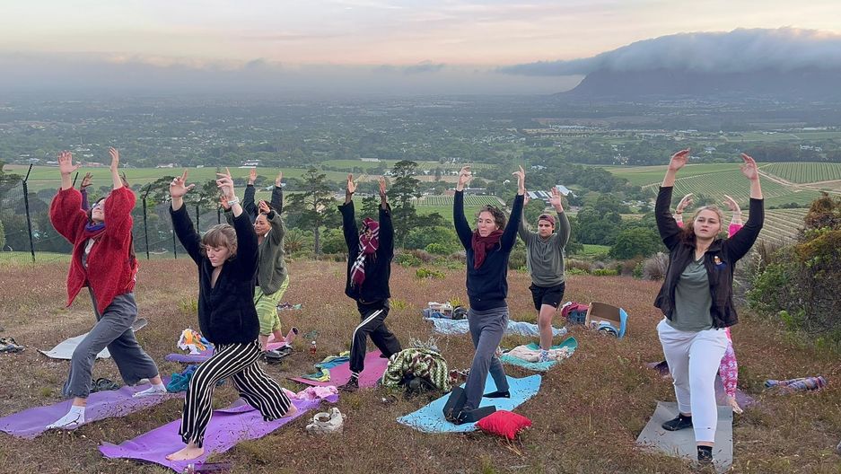 Yoga on mats outdoors with a mountain behind